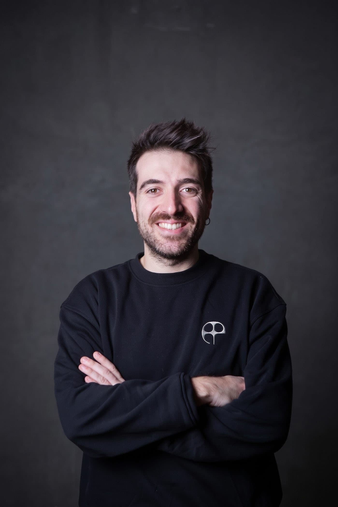 Pierluigi Amati, cloud architect, a braccia conserte su fondo grafite
