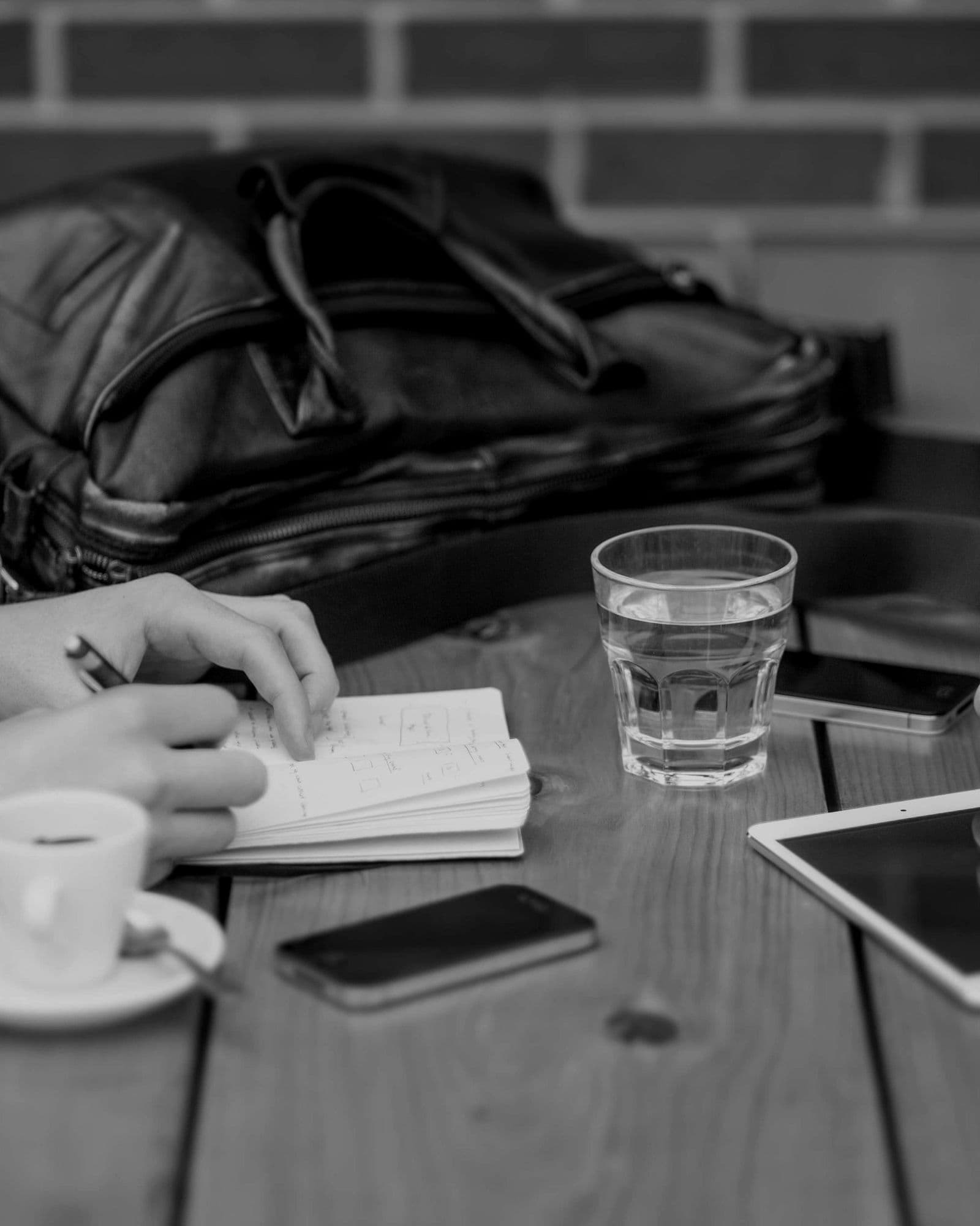 Due persone prendono appunti a un tavolo di lavoro con tablet e telefono